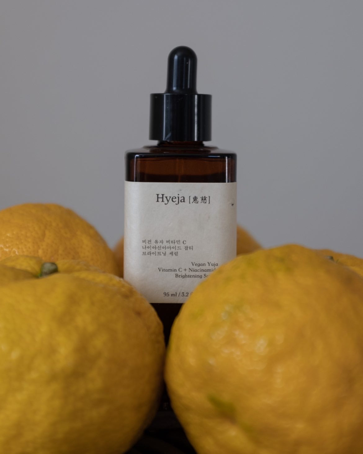 Hyeja Vegan Yuzu Vitamin C + Niacinamide Brightening Serum surrounded by fresh yuzu fruits, highlighting natural ingredient inspiration