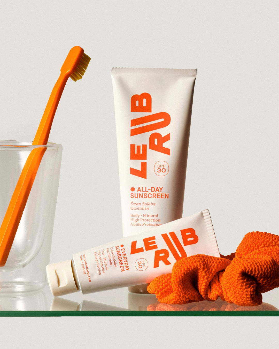 Le Rub All-Day Sunscreen SPF 30 mineral sunscreen products with orange-toned styling, showcasing minimalist packaging and design
