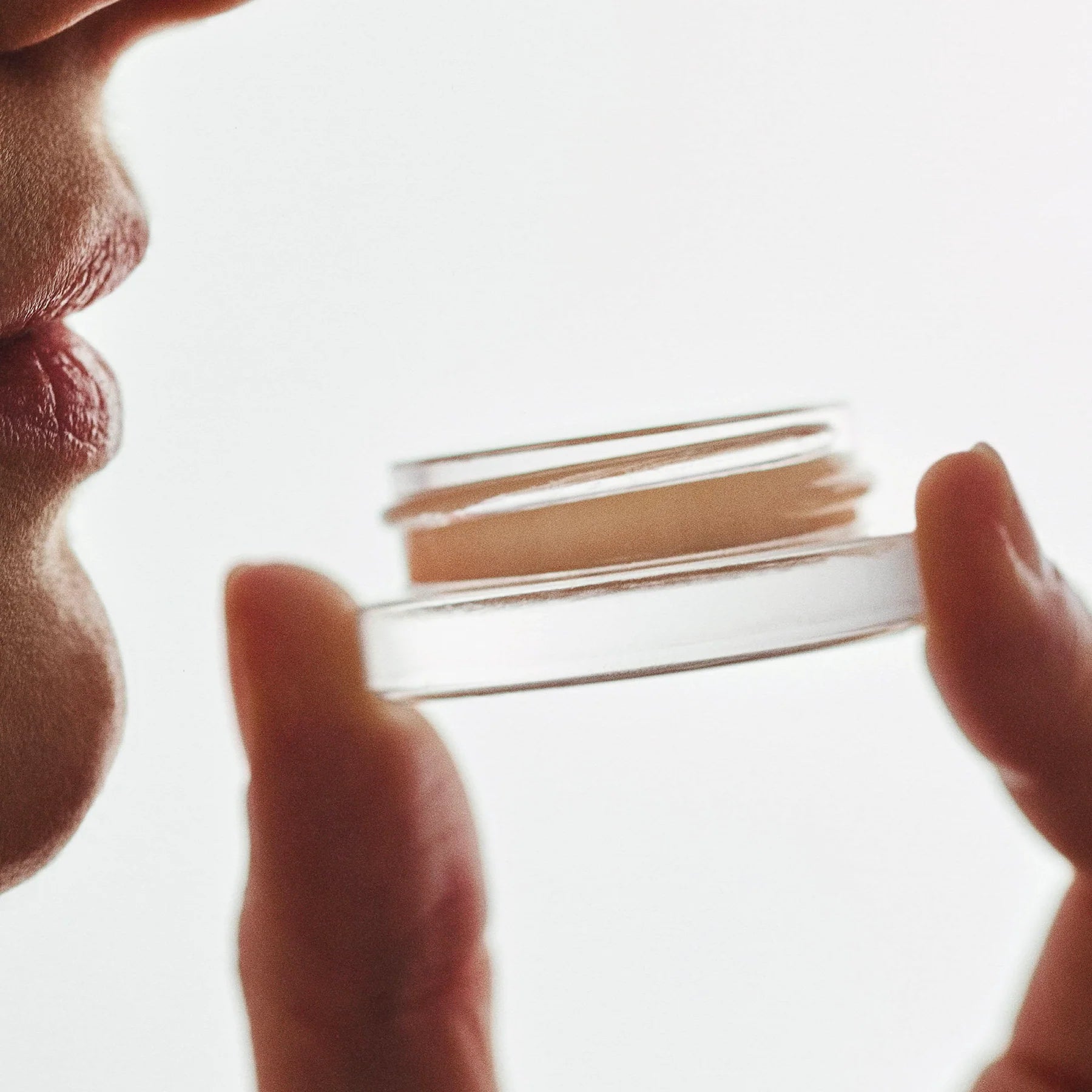 PERS Lips and Cheeks Glow Balm being held delicately, showcasing multi-use beauty product with warm, editorial lighting and intimate styling