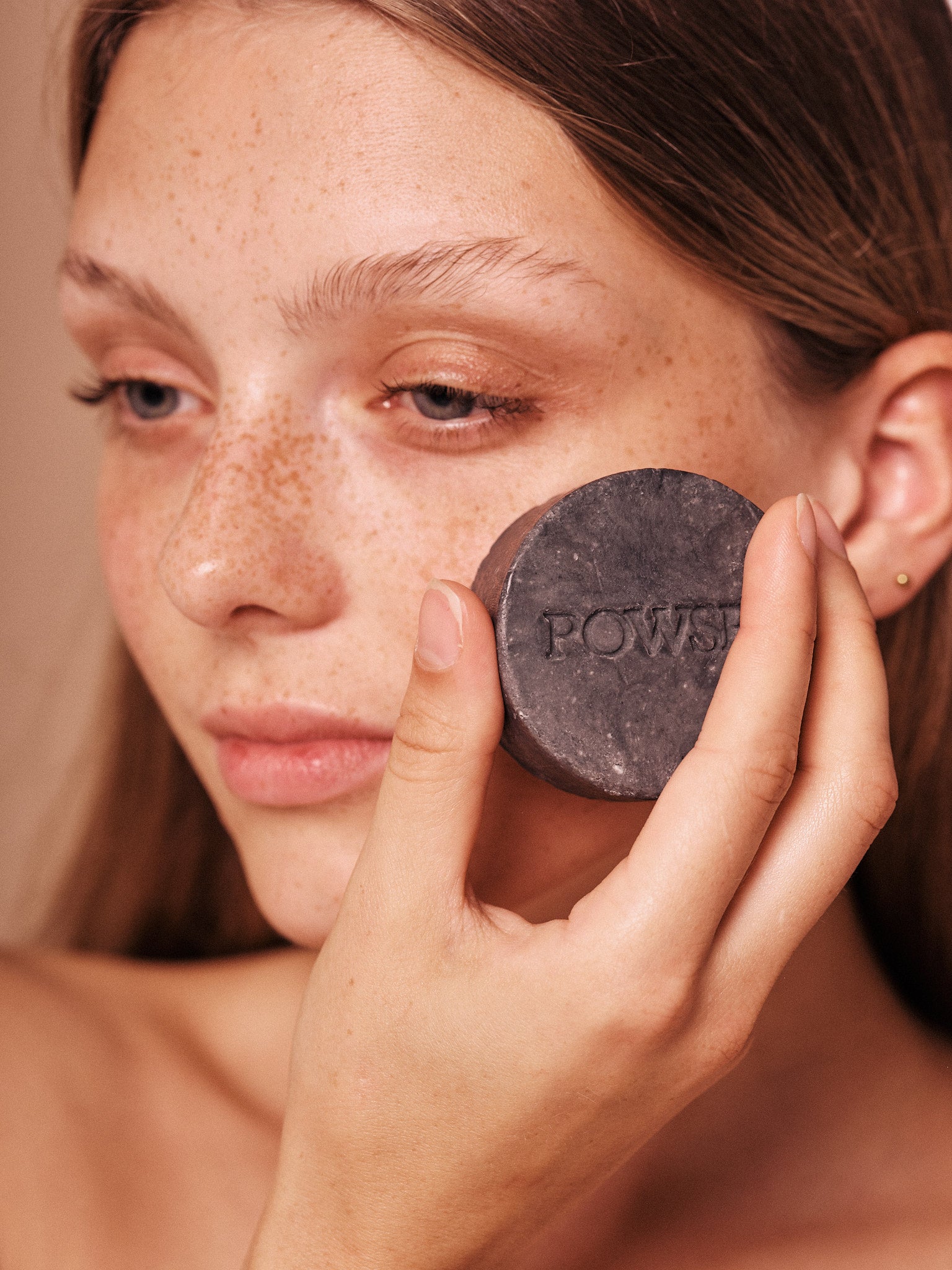 ROWSE Charcoal Face Cleanser solid bar being applied by a model with freckles, showcasing natural skincare and minimalist beauty routine