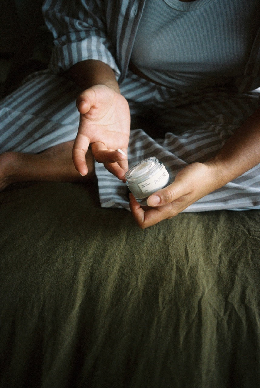 ROWSE Melatonin Sleeping Mask held in cupped hands during bedtime routine, showcasing intimate nighttime skincare ritual with soft, cozy lighting