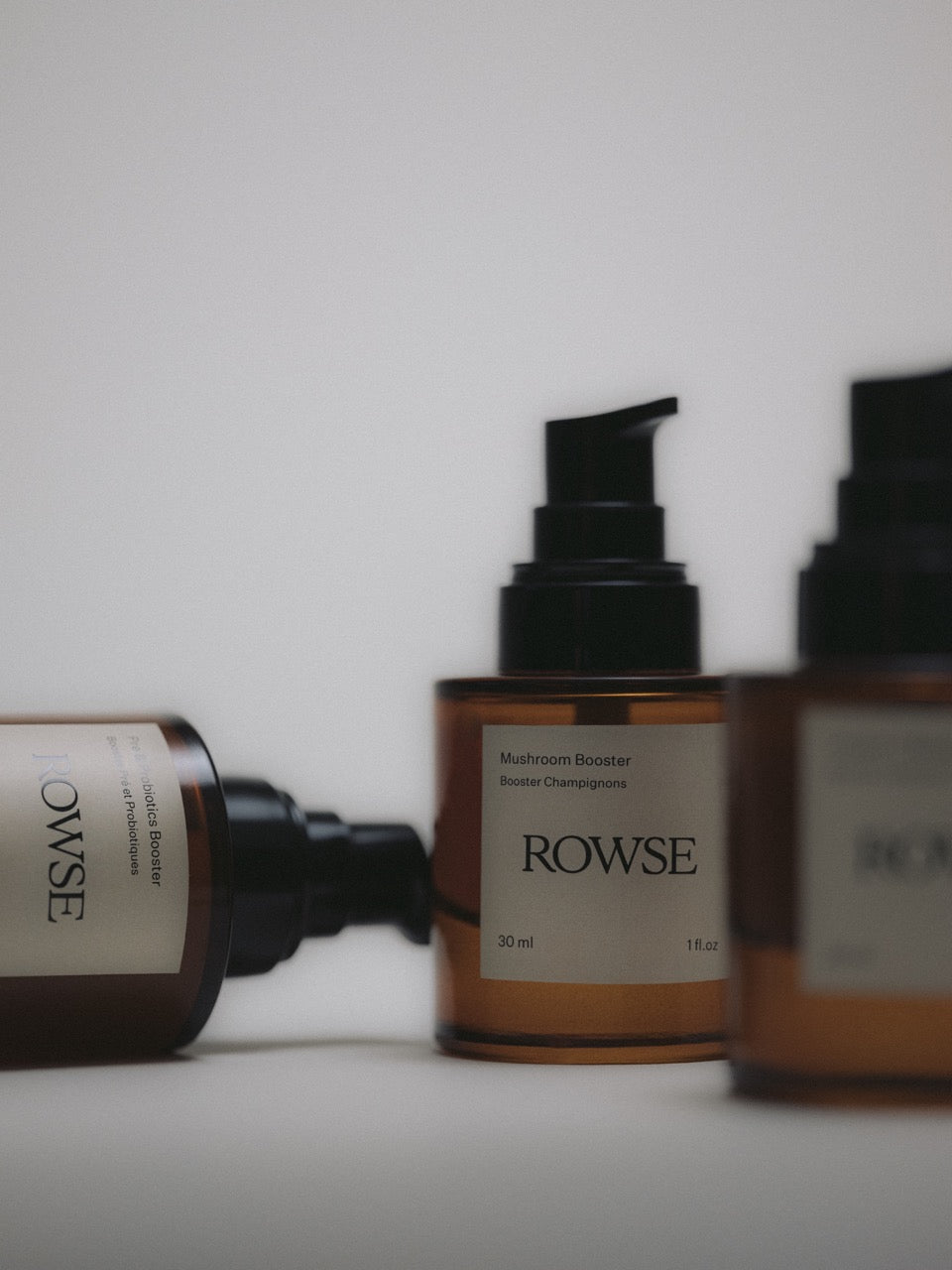 ROWSE Mushroom Booster in amber glass bottles with black pumps, showcasing minimalist skincare design with multiple product variants