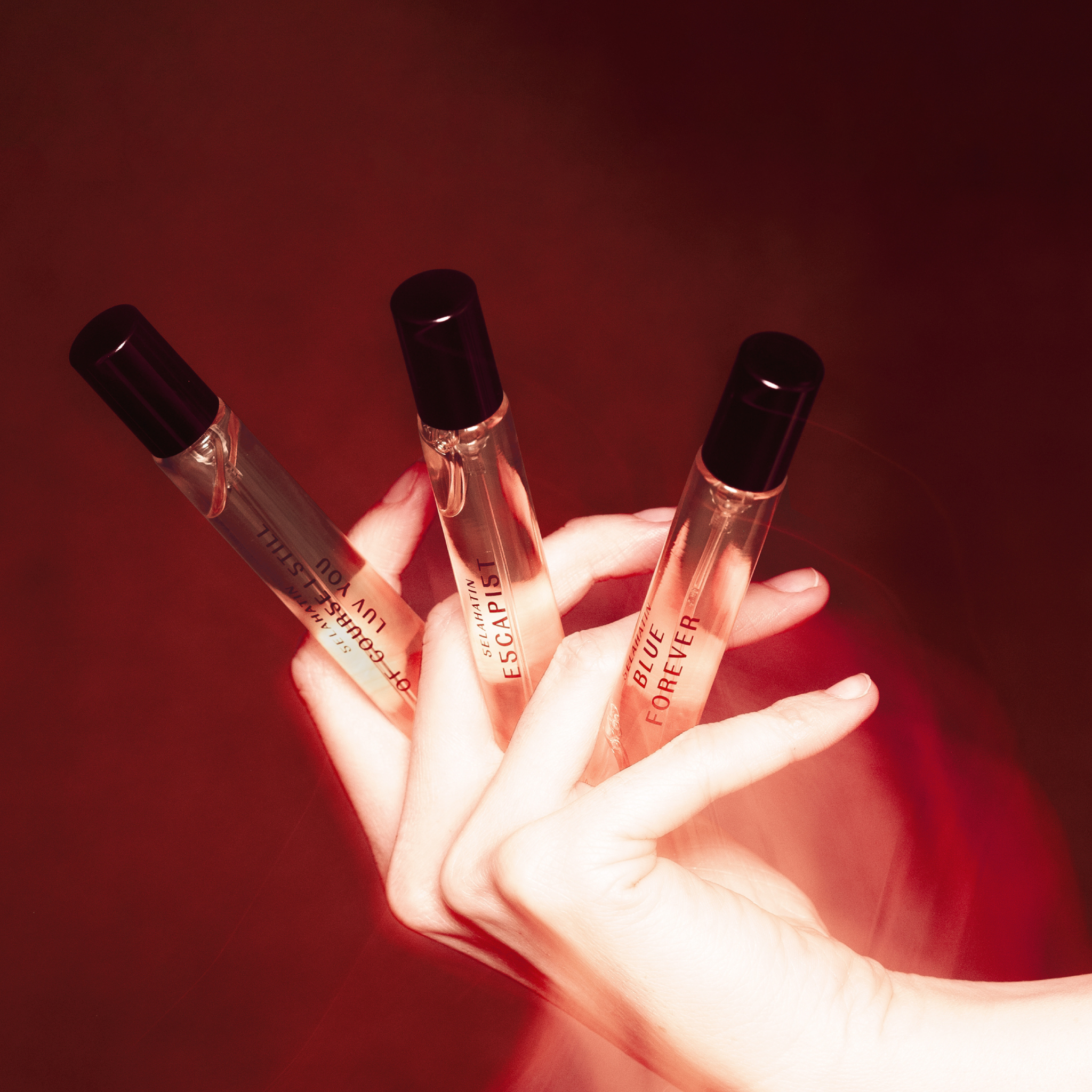 Selahatin oral spray collection in glass bottles, artistic red-toned editorial image showcasing product range with dramatic lighting