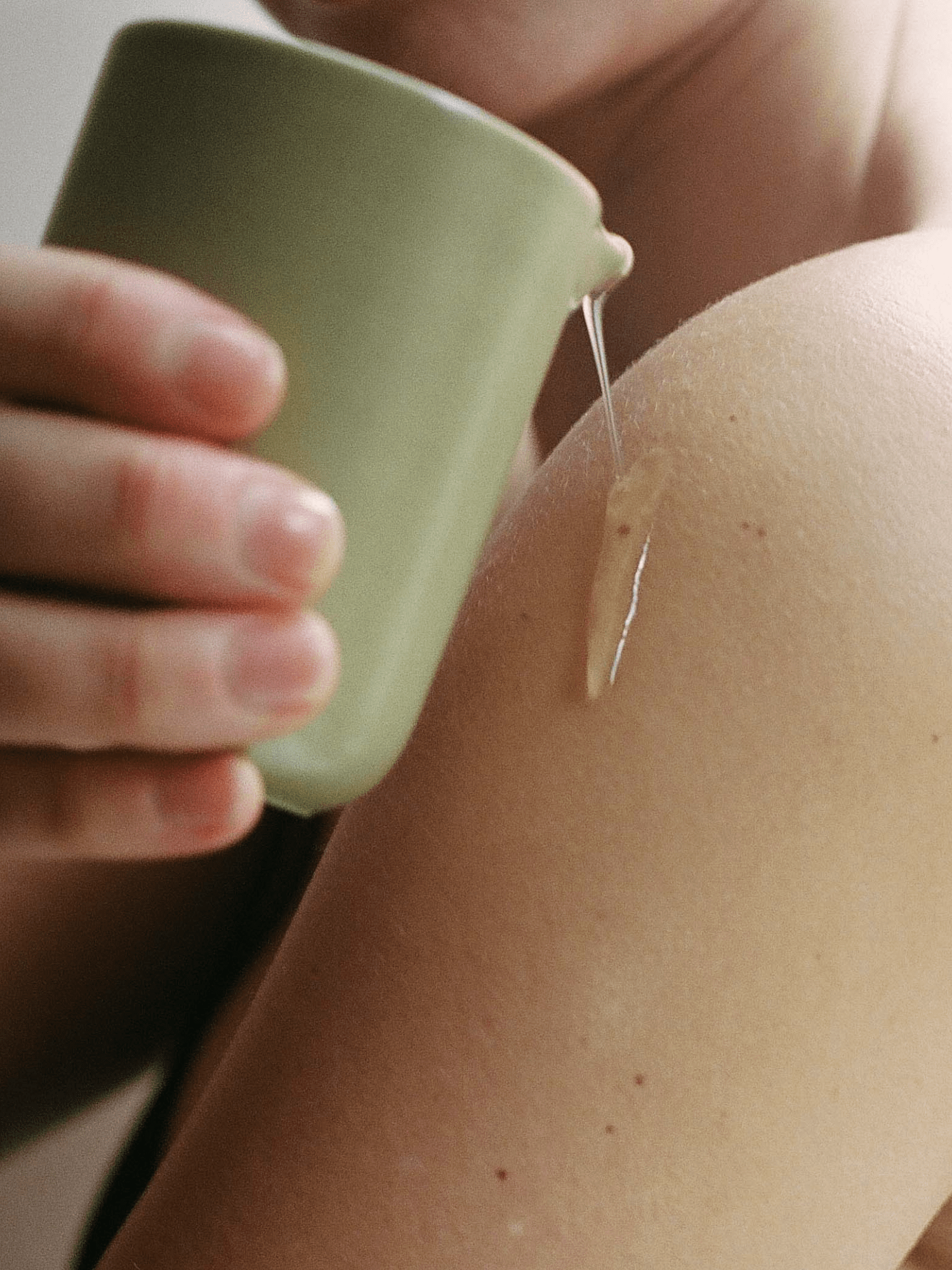 SITRE Night Touch Massage Candle being applied, showcasing warm oil droplet on skin with soft green candle holder, emphasizing intimate wellness ritual