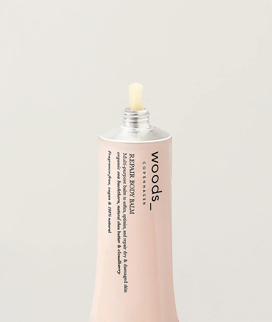 Woods Copenhagen Repair Body Balm in soft pink packaging with minimalist design, showcasing multi-purpose skincare balm with silver dropper cap