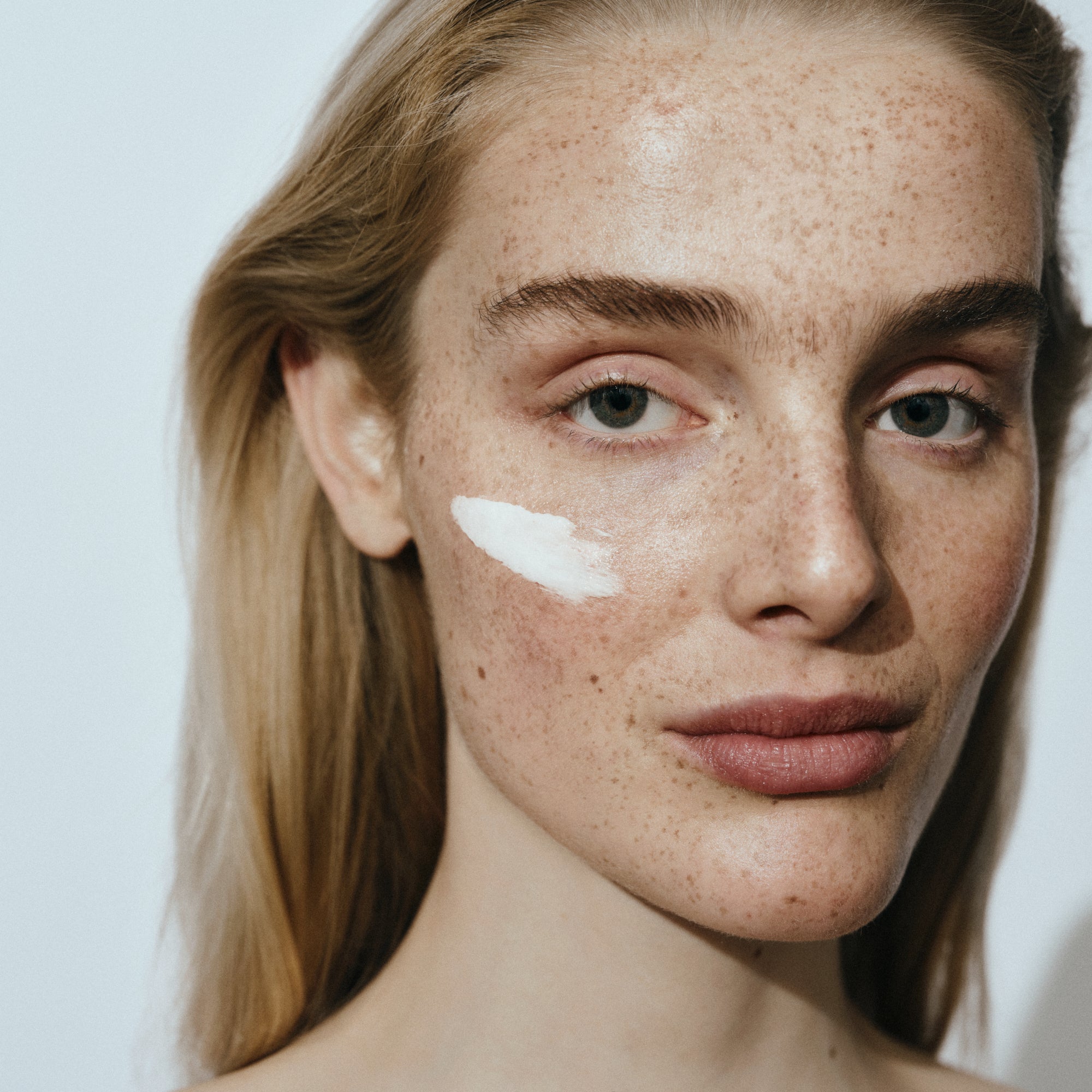 Close-up of model with face cream on cheek, representing clean skincare from TYPEYOURSKIN in Nicosia.