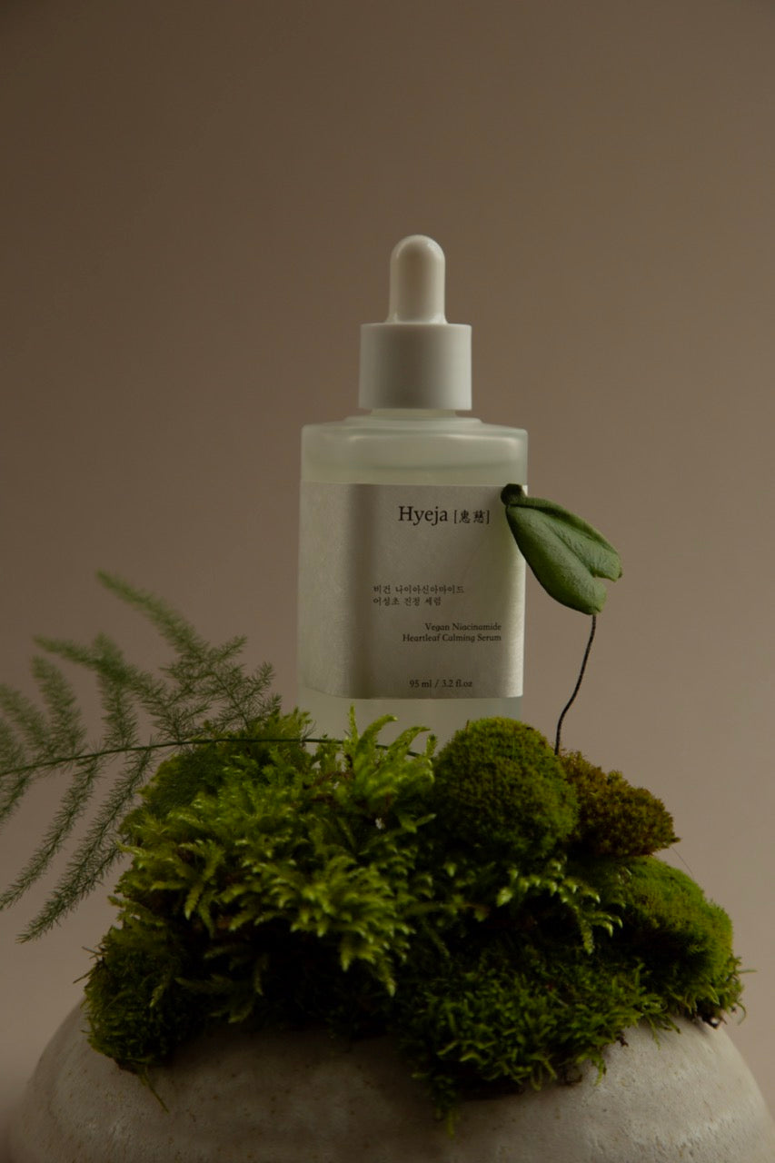 Hyeja Vegan Niacinamide Heartleaf Calming Serum positioned on lush green moss, highlighting natural botanical ingredients and minimalist Korean skincare design