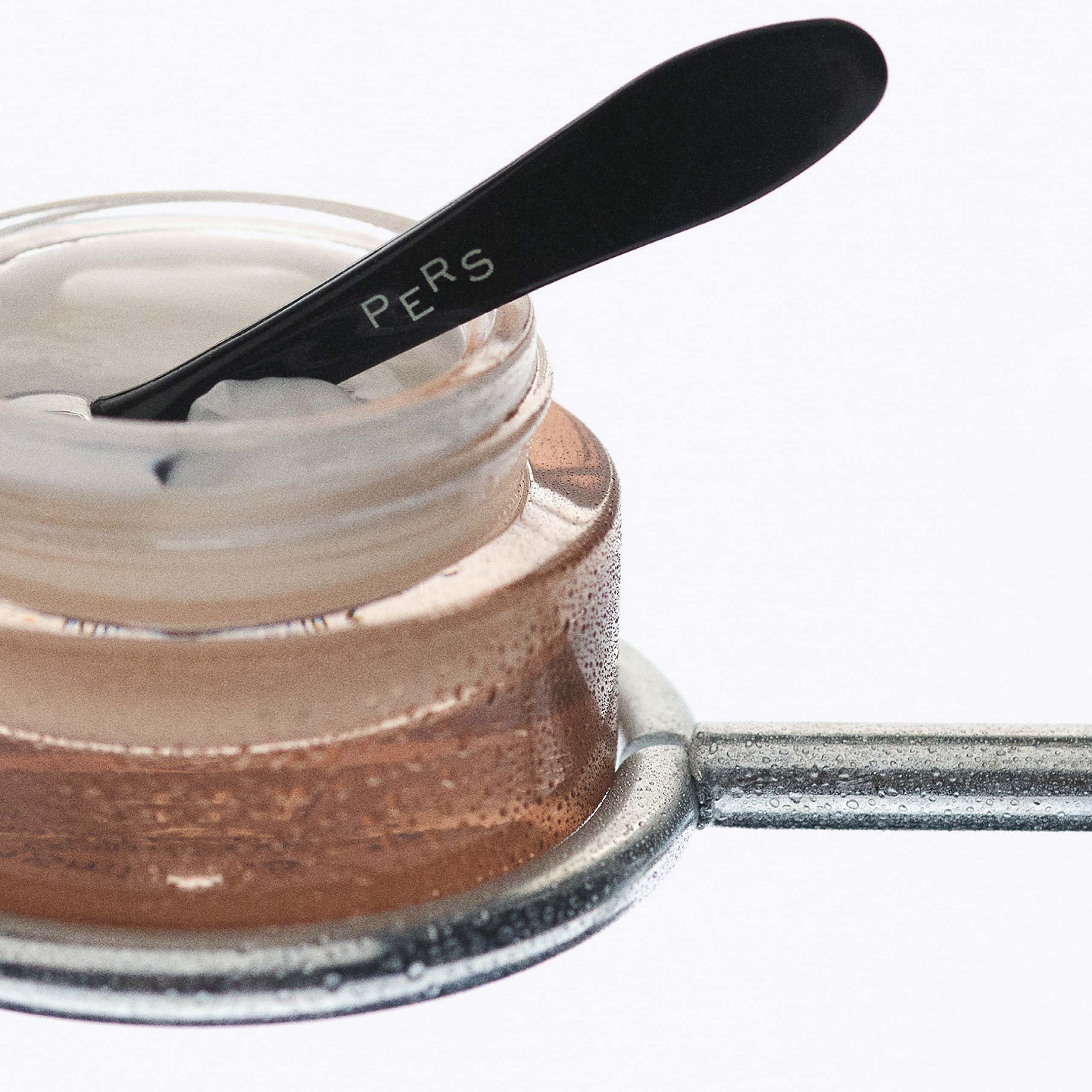 PERS Eye Cream in glass jar with black applicator spoon, showcasing luxurious skincare product with precise application tool for delicate eye area
