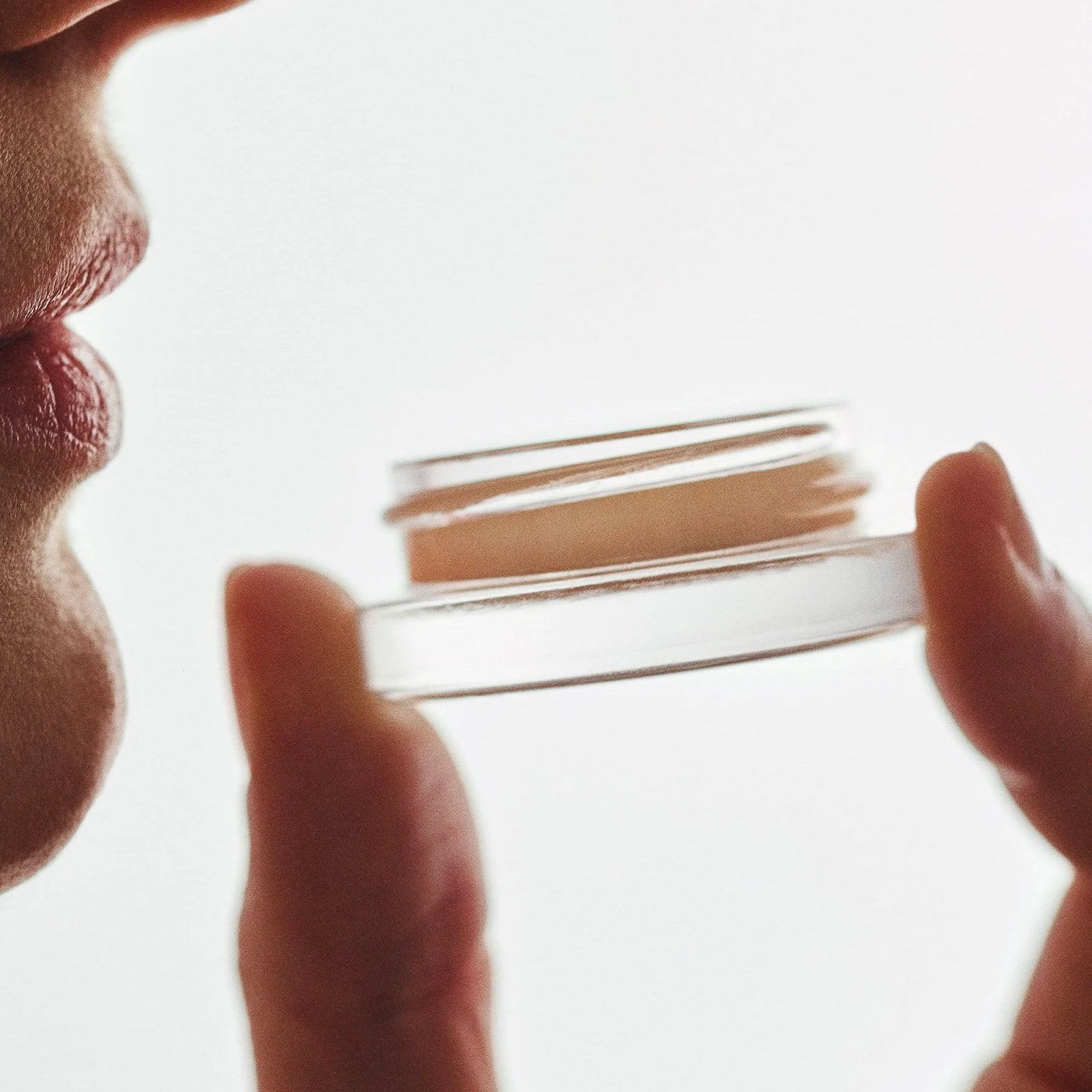 PERS Lips and Cheeks Glow Balm being held delicately, showcasing multi-use beauty product with warm, editorial lighting and intimate styling
