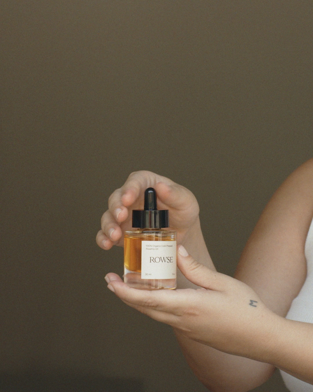 ROWSE Organic Rosehip Oil being carefully applied, demonstrating precise skincare routine and natural oil absorption technique
