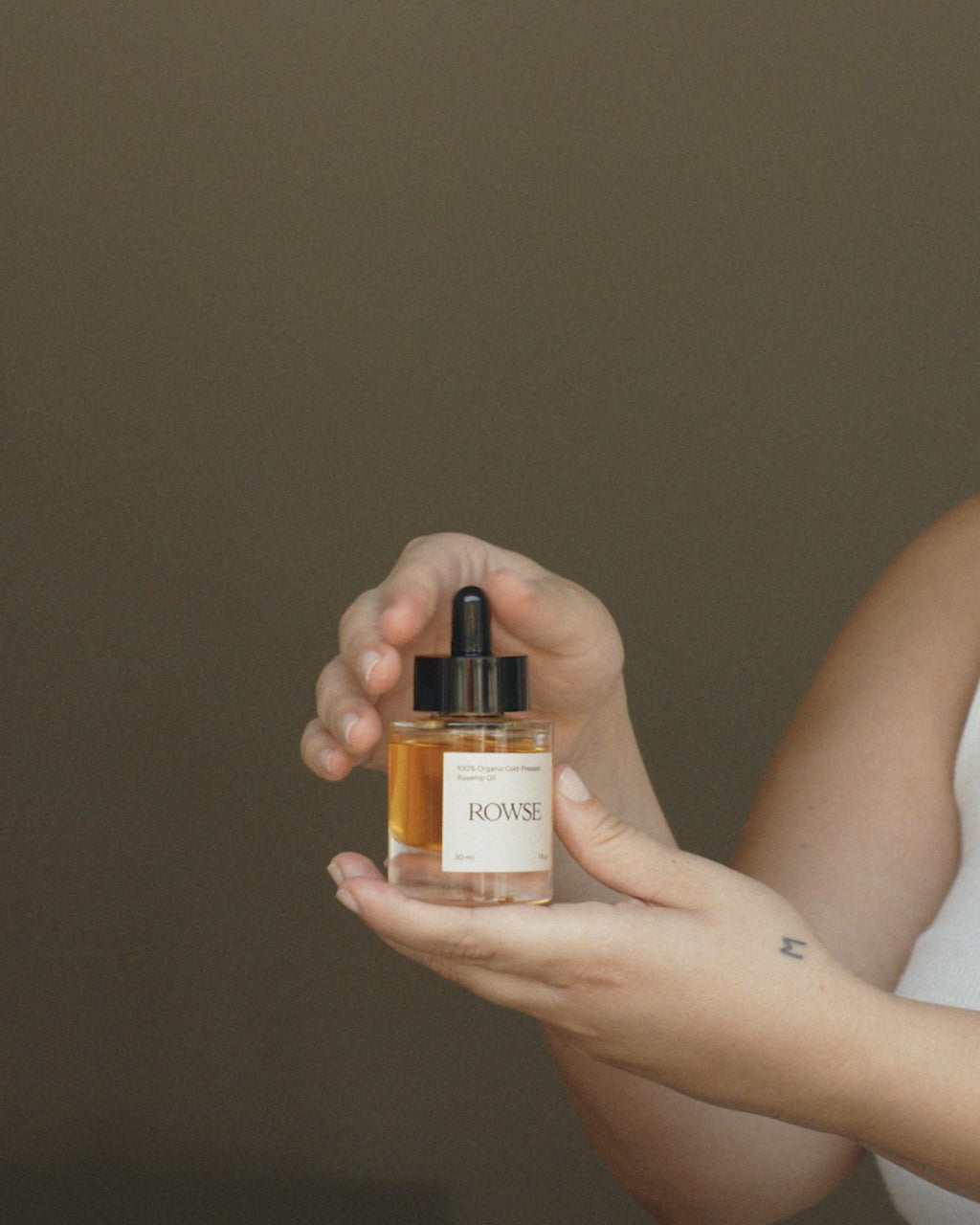 ROWSE Organic Rosehip Oil being carefully applied, demonstrating precise skincare routine and natural oil absorption technique
