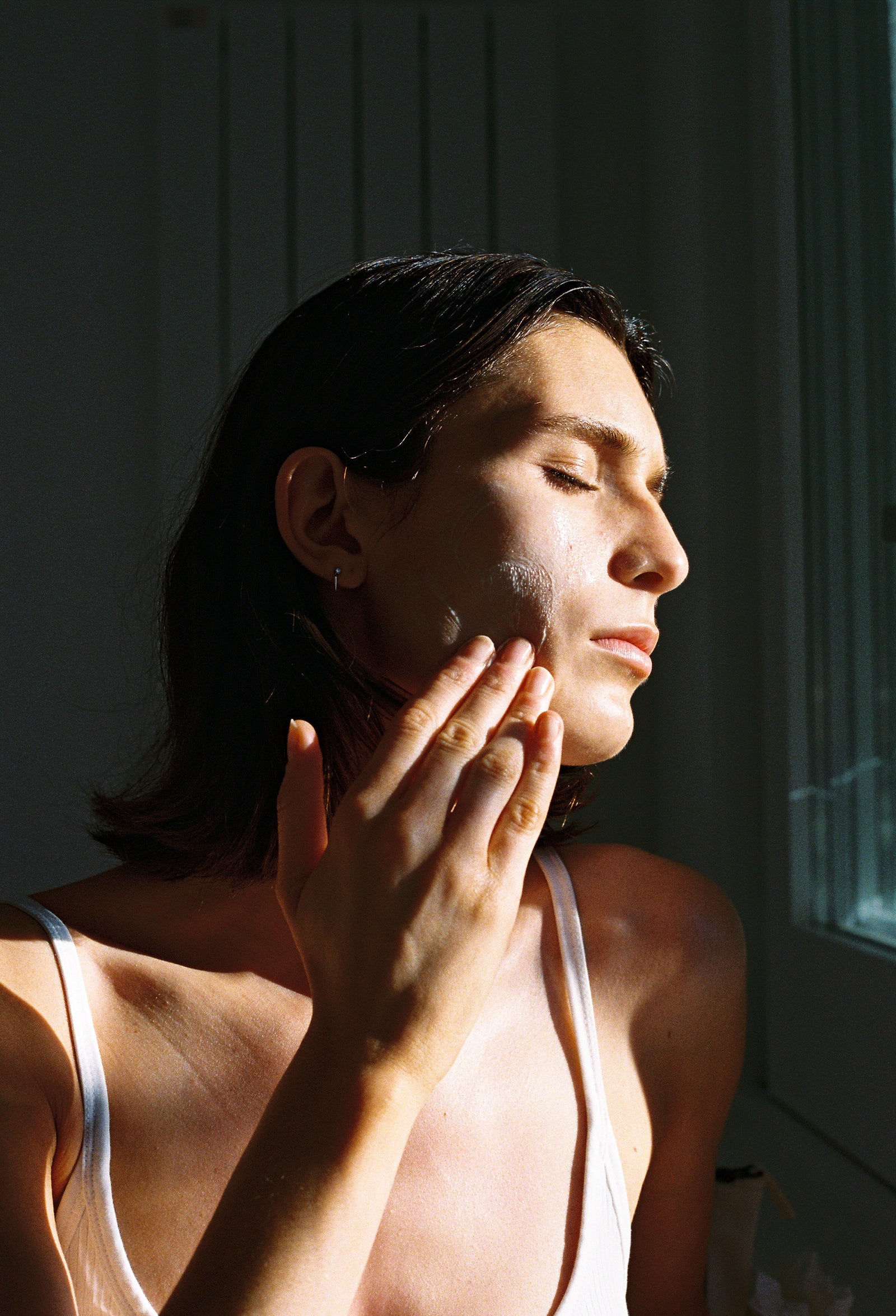ROWSE Melatonin Sleeping Mask showcased through an intimate, editorial portrait of a woman applying skincare, capturing soft natural light and peaceful moment
