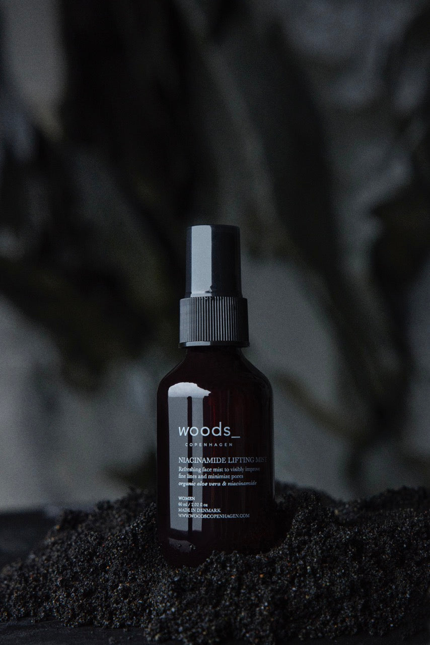Scandinavian skincare minimalism - Woods Copenhagen Niacinamide Lifting Mist with 5% Vitamin B3, positioned on natural rock surface, highlighting clean beauty aesthetic