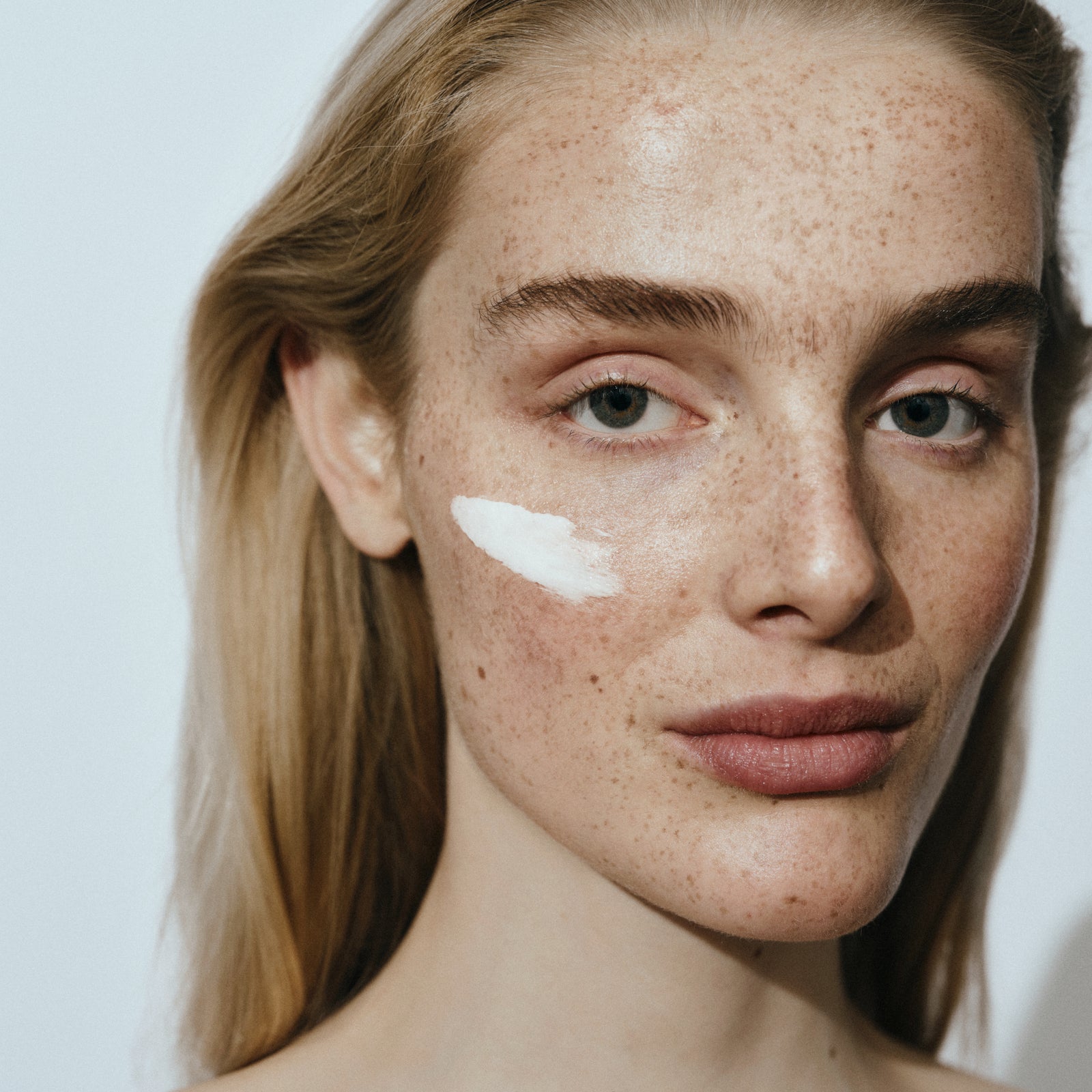Woods Copenhagen skincare product being applied by model with natural freckles, showcasing inclusive beauty and clean skincare routine
